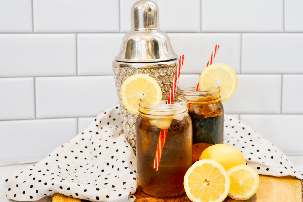 Long Island Iced Tea - Two drinks in jars with ice and a lemon circle as a garnish. 