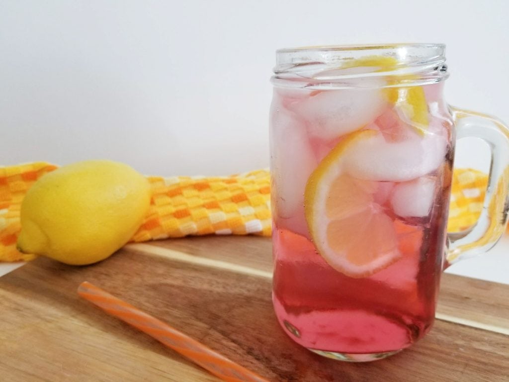 orange and cranberry vodka cocktail with full lemon beside it 