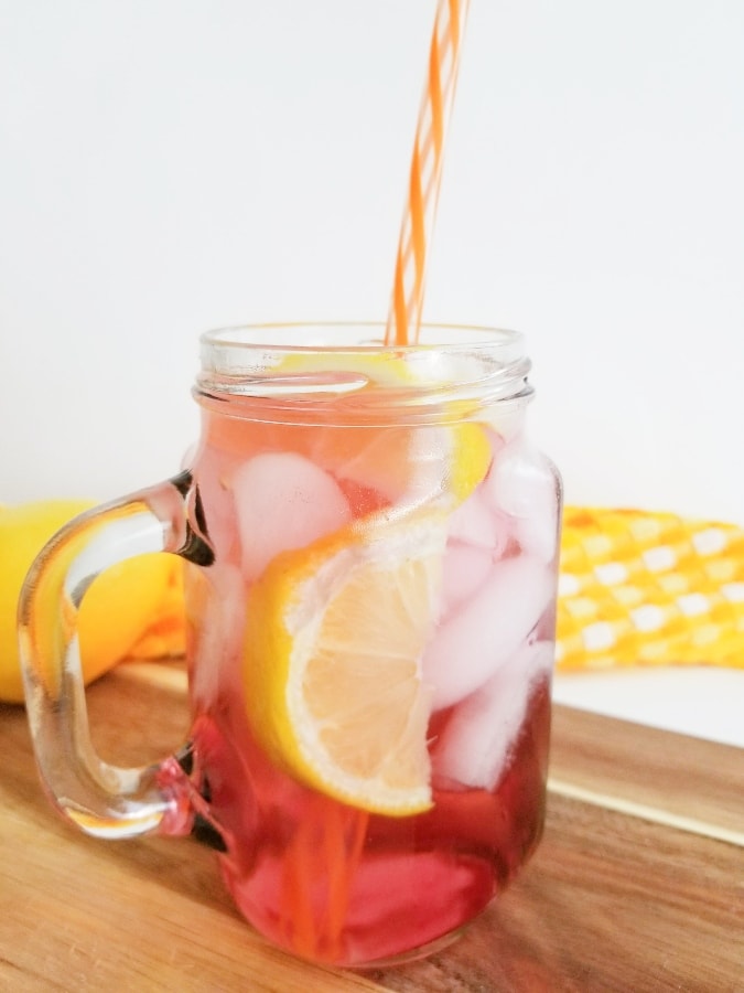 Orange and cranberry vodka cocktail with ice and lemon wedge in it 