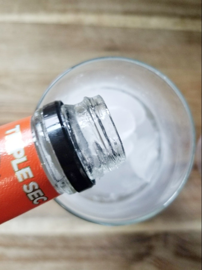 triple sec being poured into ice filled glass 