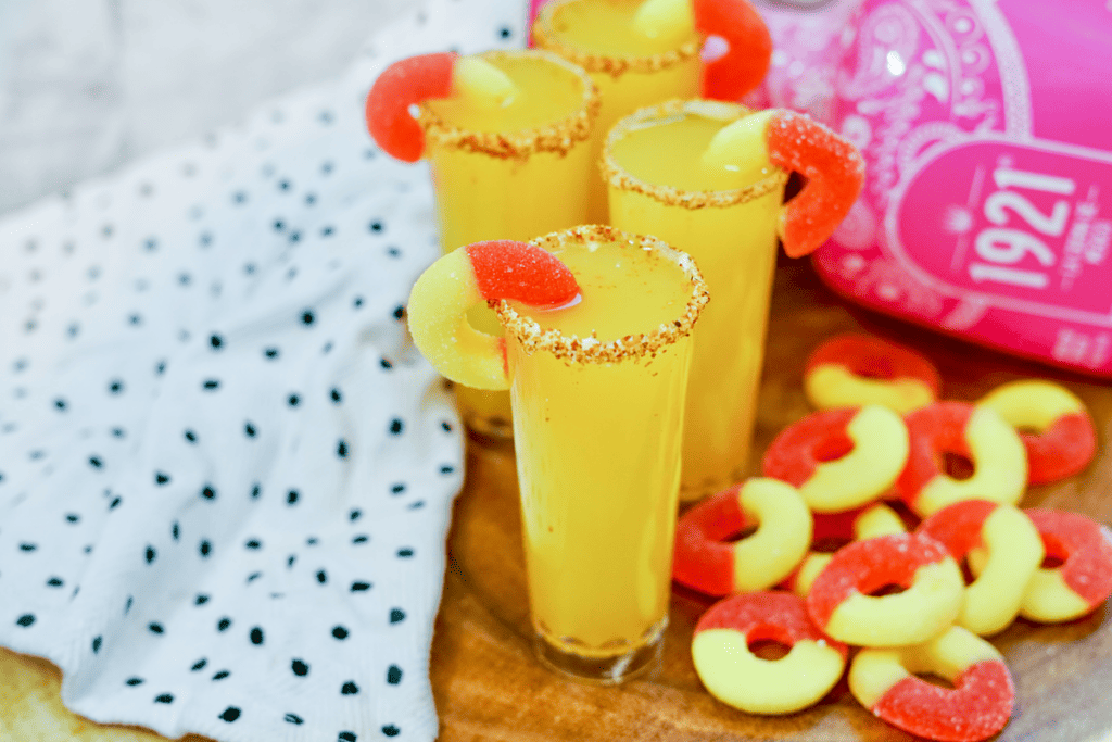 Peach Margarita Shooters - four shooters with gummy peach rings beside it. 