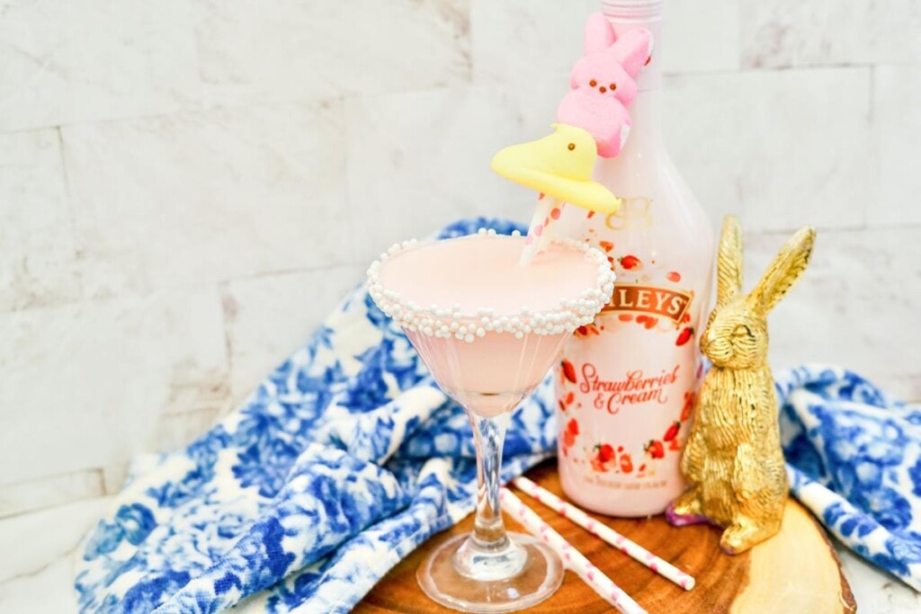 Peeps Martini Recipe: Showing a pink drink in a martini rimmed with sprinkles, with a yellow peep and a pink bunny peep on a straw sticking out. 