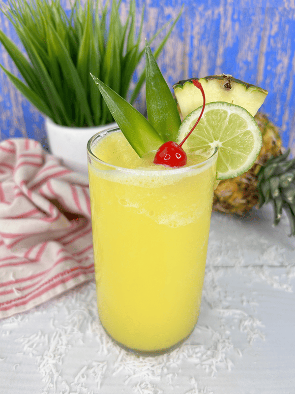 Pineapple Rum Slush with pineapple stems, lime, cherries, and pineapple wedge as garnish. 