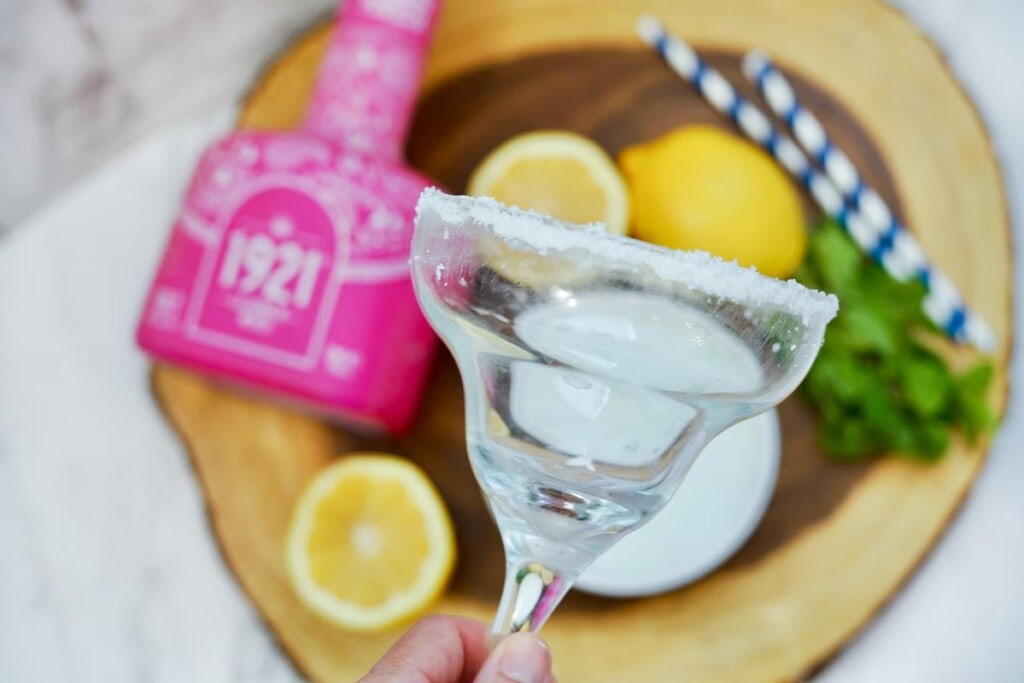 Pink Senorita Cocktail Recipe - Hand holding a margarita glass with a salted rim. 