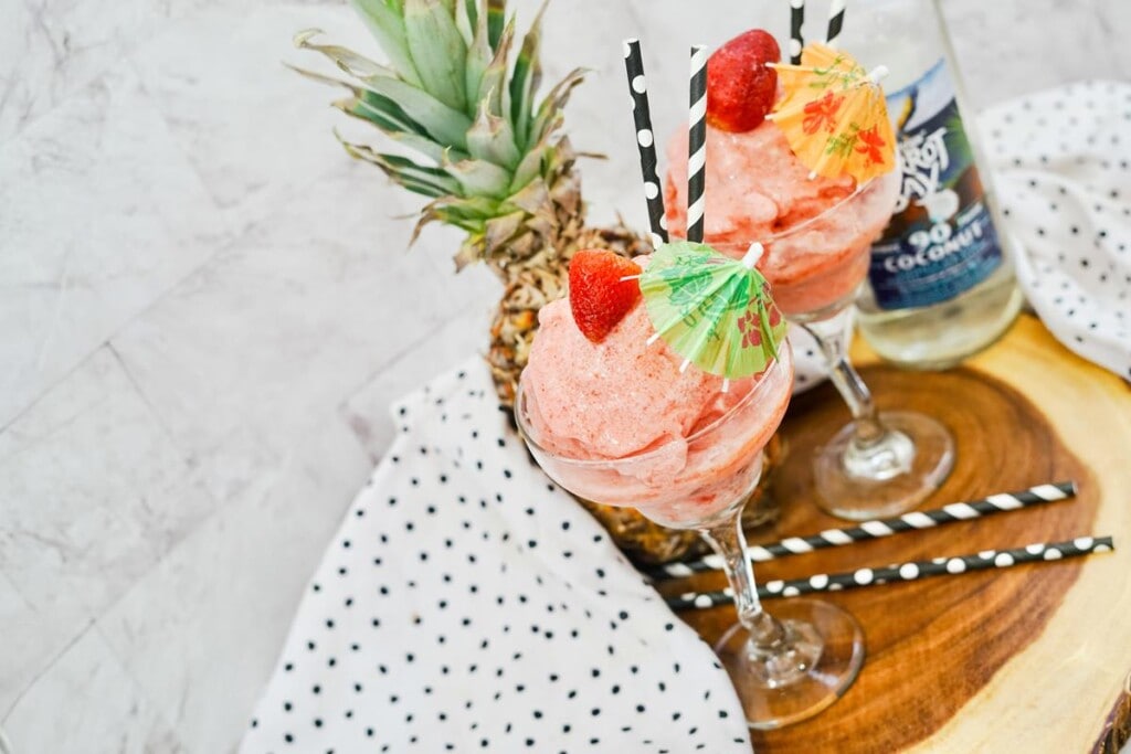 Frozen Strawberry Colada Recipe - Cocktails topped with fresh strawberry, paper umbrellas, and black an white straws. 