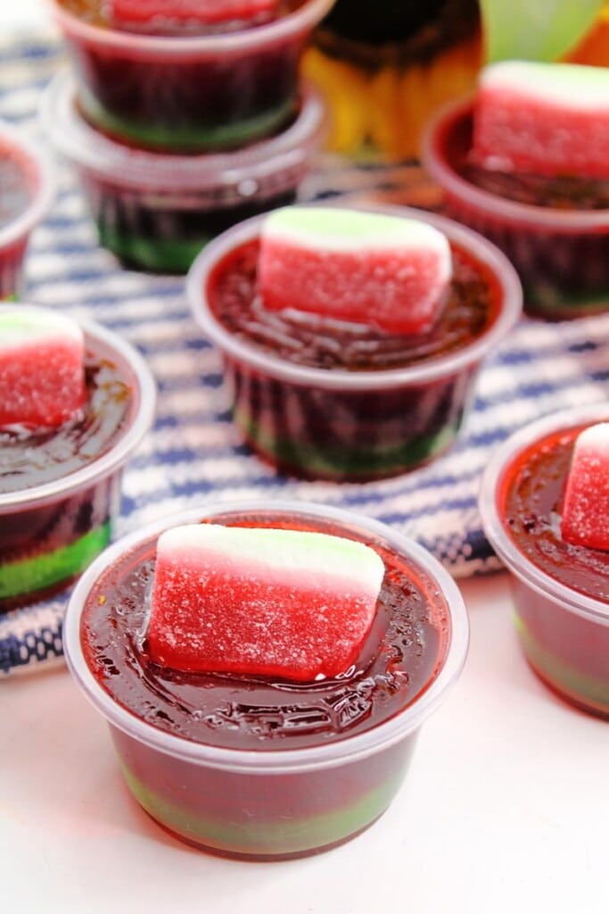 above shot of watermelon jello shot showing sugared sour watermelon candy on top o fred jello layer. 